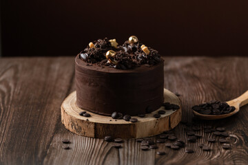 front view of chocolate cake, with chocolate chips, spoon and wooden table.