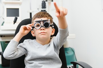 Cheerful child boy in glasses checks eye vision pediatric ophthalmologist.