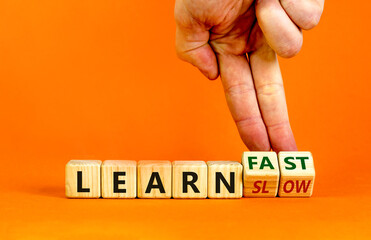 Learn slow or fast symbol. Businessman turns wooden cubes and changes words 'learn slow' to 'learn fast'. Beautiful orange background, copy space. Business and learn slow or fast concept.