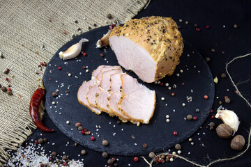 Appetizing baked sliced meat on slate board and black background close-up