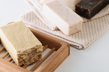 natural handmade soap on a wooden soap dish, side view, on a bath towel, light background