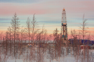 The landscape of the northern landscape of an oil and gas field with a drilling rig against the...