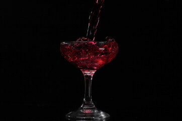 Pouring drink into the glass with black background