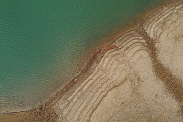 Aerial top view pattern of clear river water and sand on the river bank