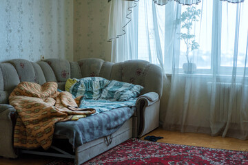Bed with crumpled blanket and not neatly folded pillows in bedroom
