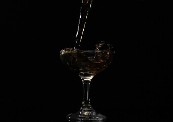 Pouring drink into the glass with black background