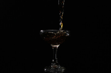 Pouring drink into the glass with black background