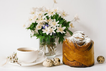 Easter card. A cake, a cup of tea, primroses in a vase and quail eggs on a light background