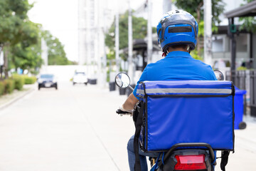 Delivery man wearing blue uniform riding motorcycle and delivery box. Motorbike delivering food or parcel express service - 415832399