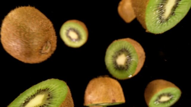 Fresh Kiwi Slices Falling on Black Background. Super Slow Motion, Wide Angle View.