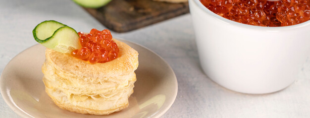 Banner with tartlets, red caviar, cucumber on a white table. Recipe for making an appetizer with red caviar. Cooking process.