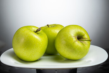 a whole green apple on a white plate