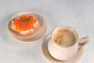 The cup of coffee and appetizer with red caviar on white background. Great breakfast. Morning concept or relax.