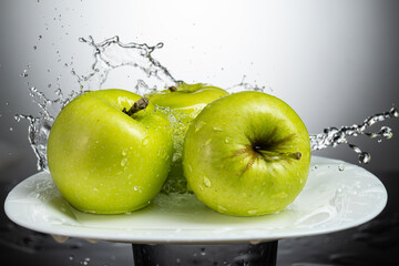 whole green apple on a white plate with splash and water flow