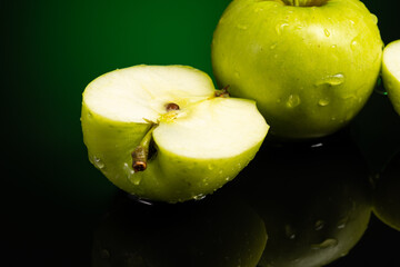 whole green apple and cut in half with splash and flow of water on dark background