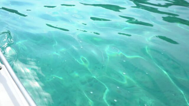 Blue sunny transparent water of sea as seen from board of moving on waves catamaran