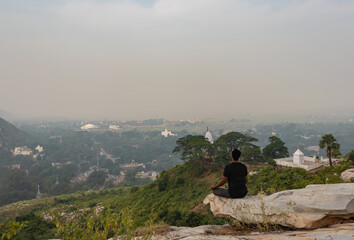 man meditating isolated at rock with amazing landscape