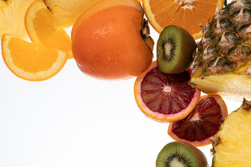 Selection of sliced fresh fruits with kiwis, pineapple, blood orange on white background with free...