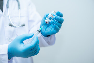 Doctor wearing blue gloves is holding  virus medicine Corona and syringes.