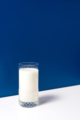 Vaso de leche fresca en mesa blanca sobre fondo azul
