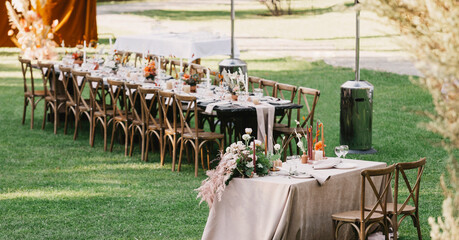 Chairs and table for newlyweds decorated with candles, served with cutlery, crockery and covered with tablecloth