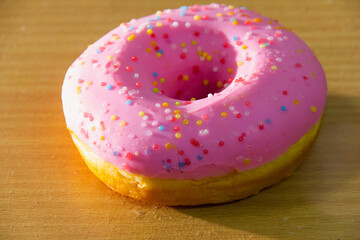 Strawberry Donuts with colorful toppings placed on wood desk with lighting reflected