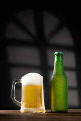 Beer mug and bottle on dark background on wooden base. with copyspace. Vertical format.