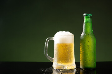 Beer mug and bottle on green background with copyspace.