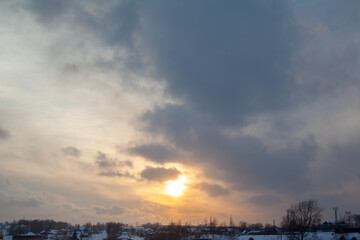 The sun among the clouds over the winter city. Beautiful background