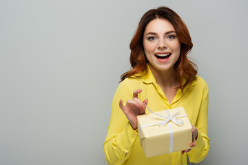 Obraz premium cheerful woman looking at camera while opening gift box on grey