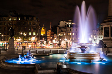 Illuminated fountain in Trafalgar Square taken at night time. - obrazy, fototapety, plakaty