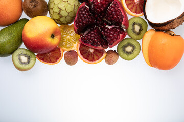 Selection of sliced fresh fruits with kiwis, pomegranate, coconut and blood orange on white...
