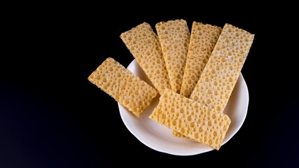 wheat fitness bread on a white saucer on a black background