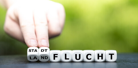 Hand dreht Würfel und ändert das Wort Landflucht in Stadtflucht.
