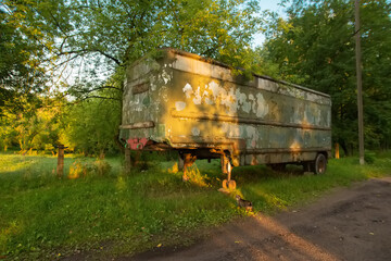 Old rusty aluminum steel metal caravan trailer painted in military khaki green in bright happy summer sunset light. Atmospheric post-apocalypse photo