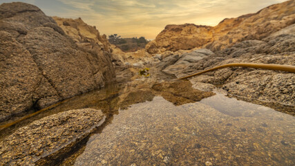 Beautiful seascape, ocean views, rocky coast, sunlight on the horizon. Composition of nature. Sunset scenery background. Cloudy sky. Water Reflection. California Seashore.