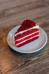Red velvet cake with beautiful layers in a white plate on a wooden table, with copy space