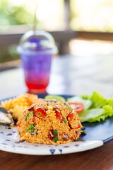 Tom Yum Fried Rice with Shrimp and Shellfish and Green Vegetables on the Side on a Unique Blue Plate and Pea Lemon Soda