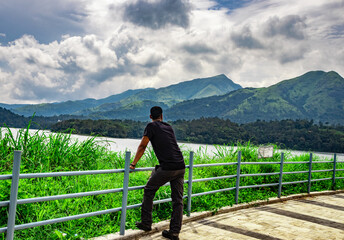 Fototapeta na wymiar man looking at pristine lake with mountain background and beautiful hiking trails