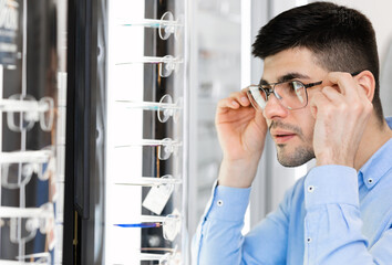 Fototapeta premium Portrait of young guy wearing spectacles near mirror