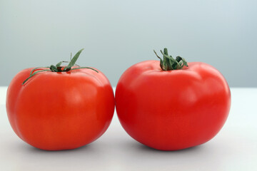 Two ripe tomatoes on a light background.