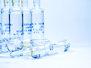 Medical ampoules and syringe on a light-coloured background.