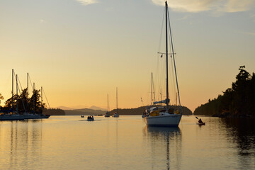 Kayaker and people in dinghy around anchored boats in Princess Bay, Wallace Island, Gulf Islands,...