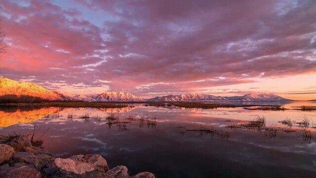 Colorful timelapse reflecting in Utah Lake looking towards the snow capped mountains where the Provo river flows into the lake.