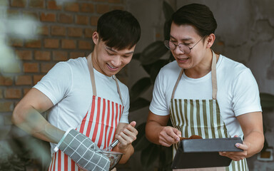 Asian men using tablet while cooking in kitchen room