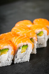 appetizing philadelphia sushi roll with salmon and avocado on a black stone plate
