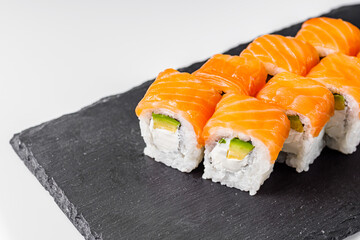 appetizing philadelphia sushi roll with salmon and avocado on a black stone plate