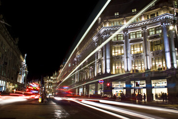 Fototapeta na wymiar Night trails of vehicles moving across the shopping area in London 's Oxford Circus.
