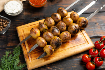 Baked potatoes grilled on three metal skewers