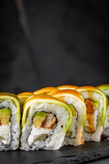 appetizing green dragon sushi roll with philadelphia cucumber eel and avocado cheese on a black stone plate